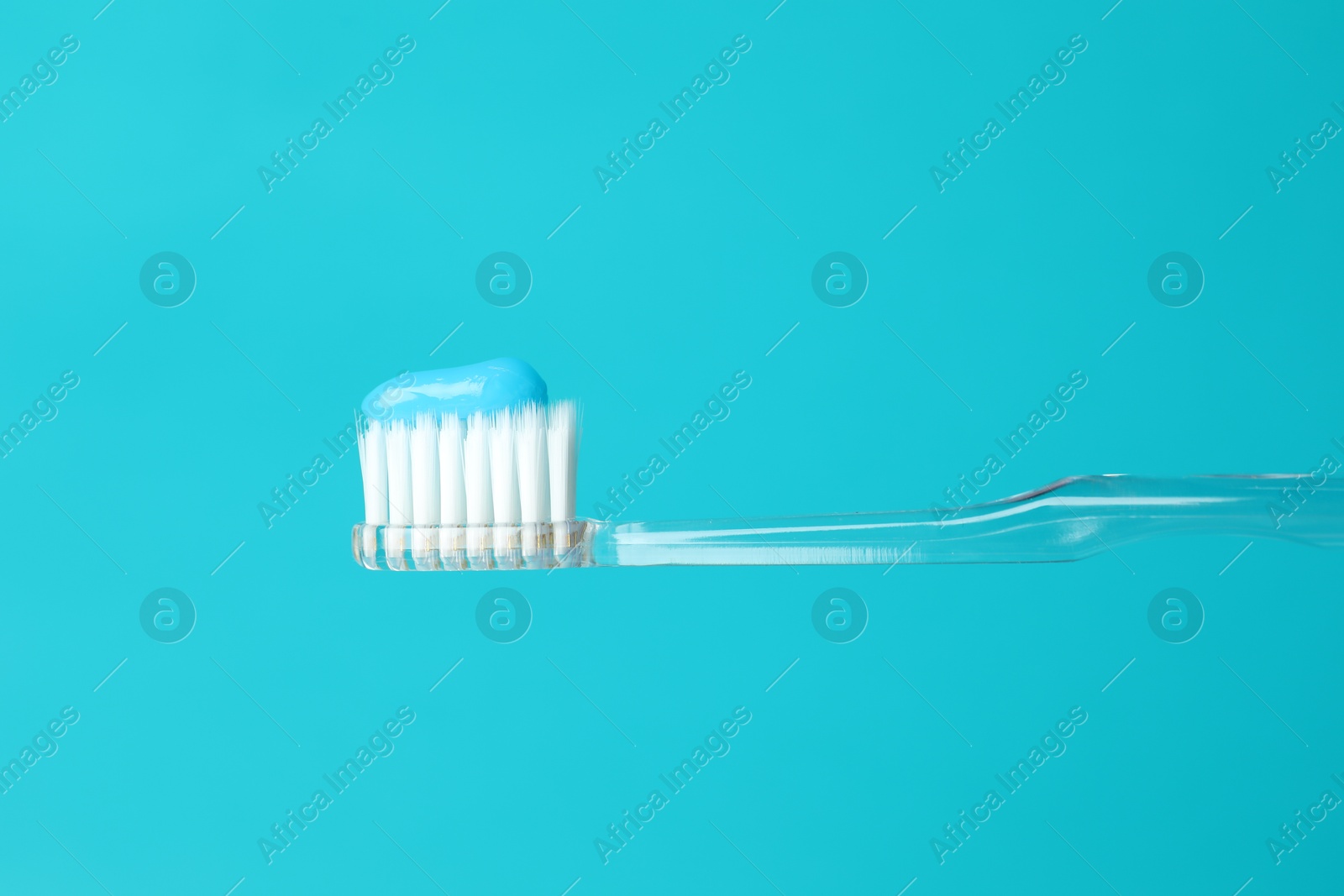 Photo of Toothbrush with toothpaste in air on light blue background, closeup