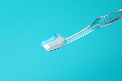 Photo of Toothbrush with toothpaste in air on light blue background, closeup. Space for text