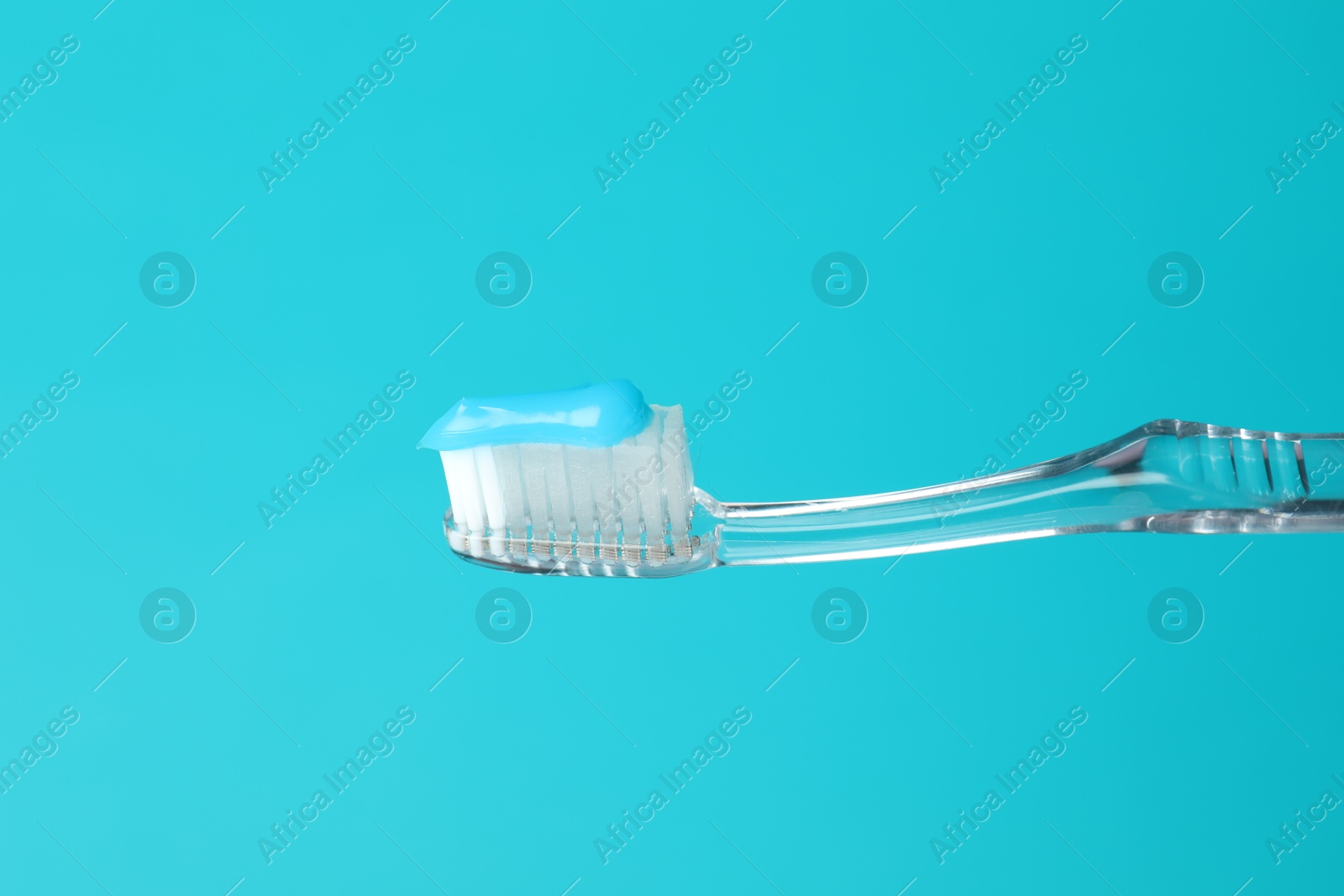 Toothbrush with toothpaste in air on light blue background, closeup. Space for text Photo of Toothbrush with toothpaste in air on light blue background, closeup. Space for text