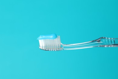 Photo of Toothbrush with toothpaste in air on light blue background, closeup. Space for text