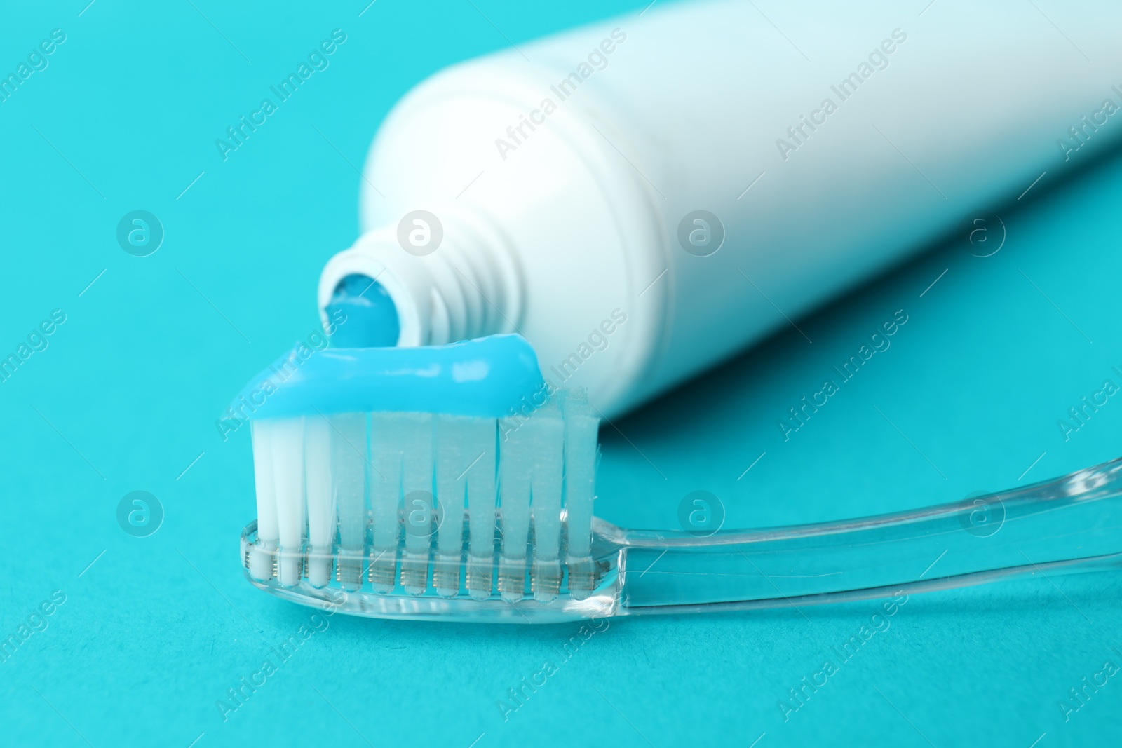 Photo of Toothbrush with toothpaste and tube on light blue background, closeup