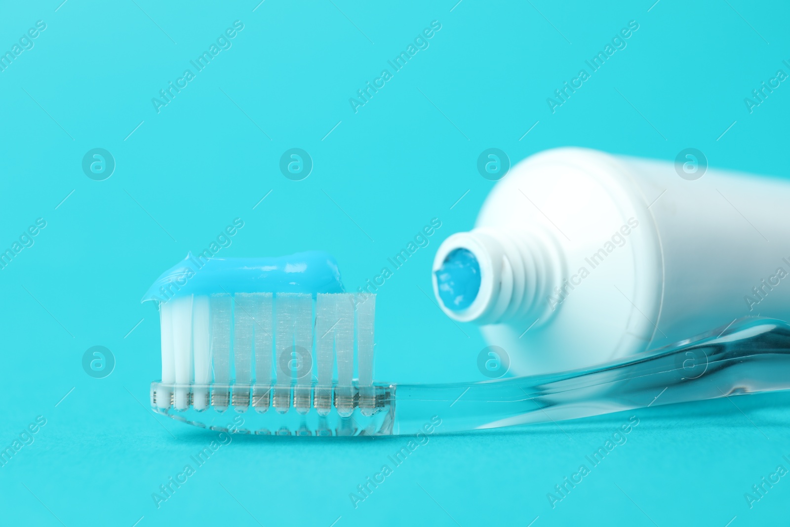 Photo of Toothbrush with toothpaste and tube on light blue background, closeup