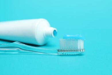 Photo of Toothbrush with toothpaste and tube on light blue background, closeup