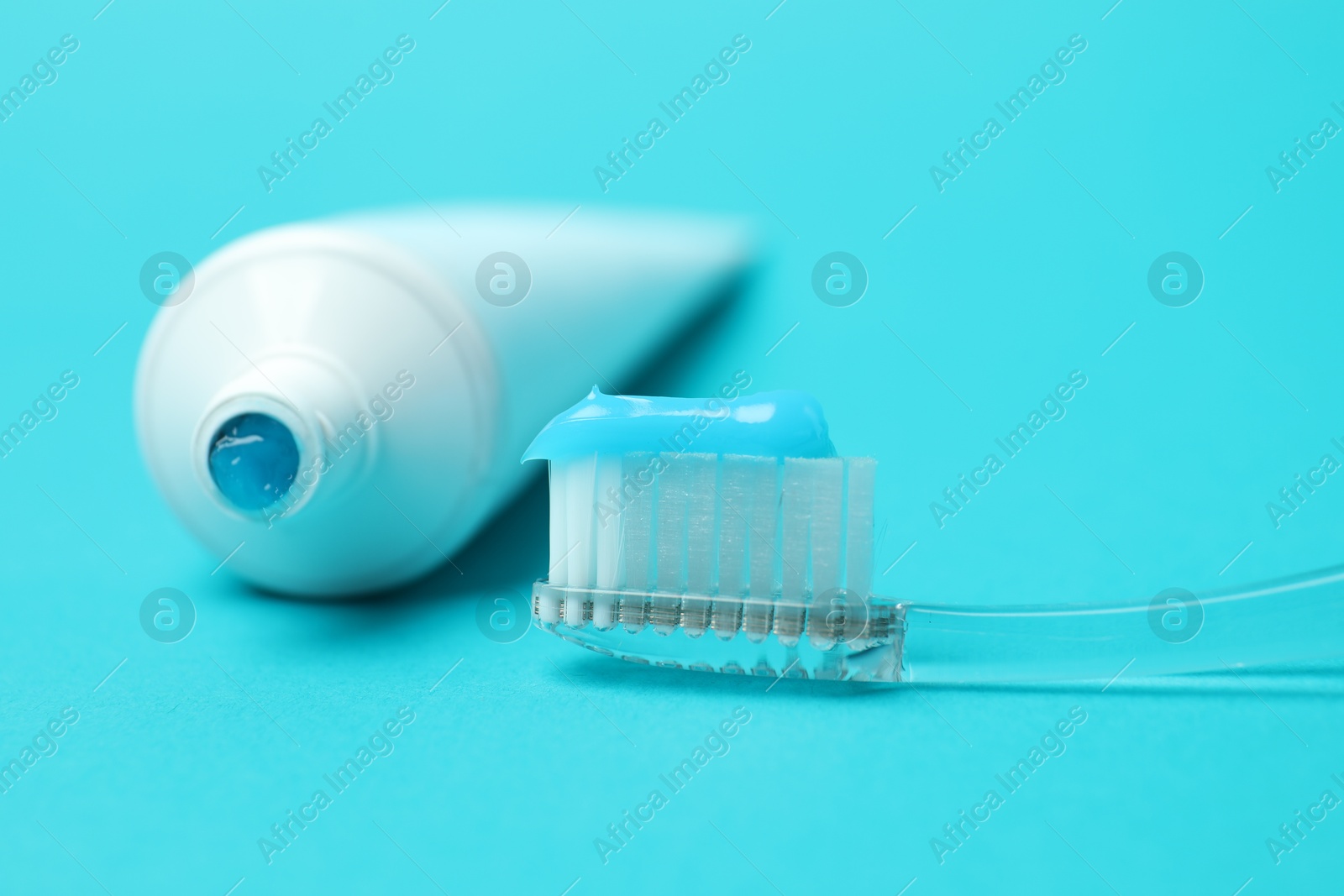 Photo of Toothbrush with toothpaste and tube on light blue background, closeup