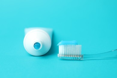 Photo of Toothbrush with toothpaste and tube on light blue background, closeup