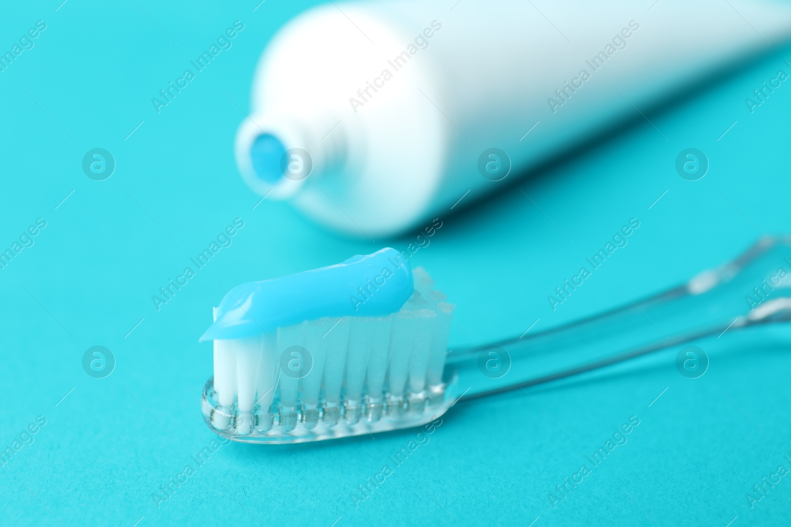 Photo of Toothbrush with toothpaste and tube on light blue background, closeup