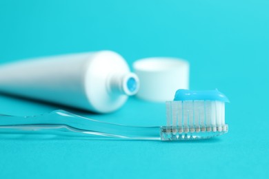 Photo of Toothbrush with toothpaste and tube on light blue background, closeup