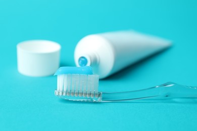 Photo of Toothbrush with toothpaste and tube on light blue background, closeup