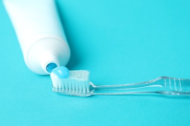 Photo of Toothbrush with toothpaste and tube on light blue background