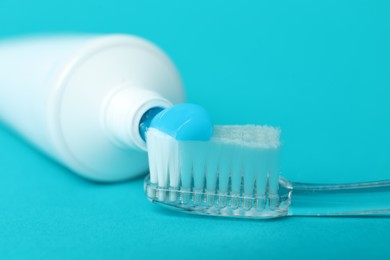 Photo of Toothbrush with toothpaste and tube on light blue background, closeup