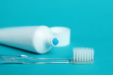 Photo of Toothbrush with toothpaste and tube on light blue background, closeup