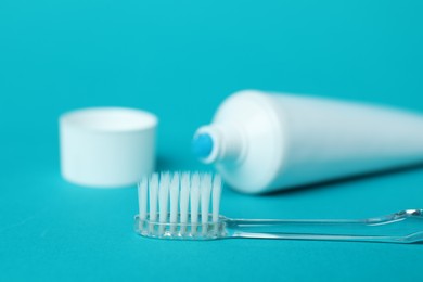 Photo of Toothbrush with toothpaste and tube on light blue background, closeup