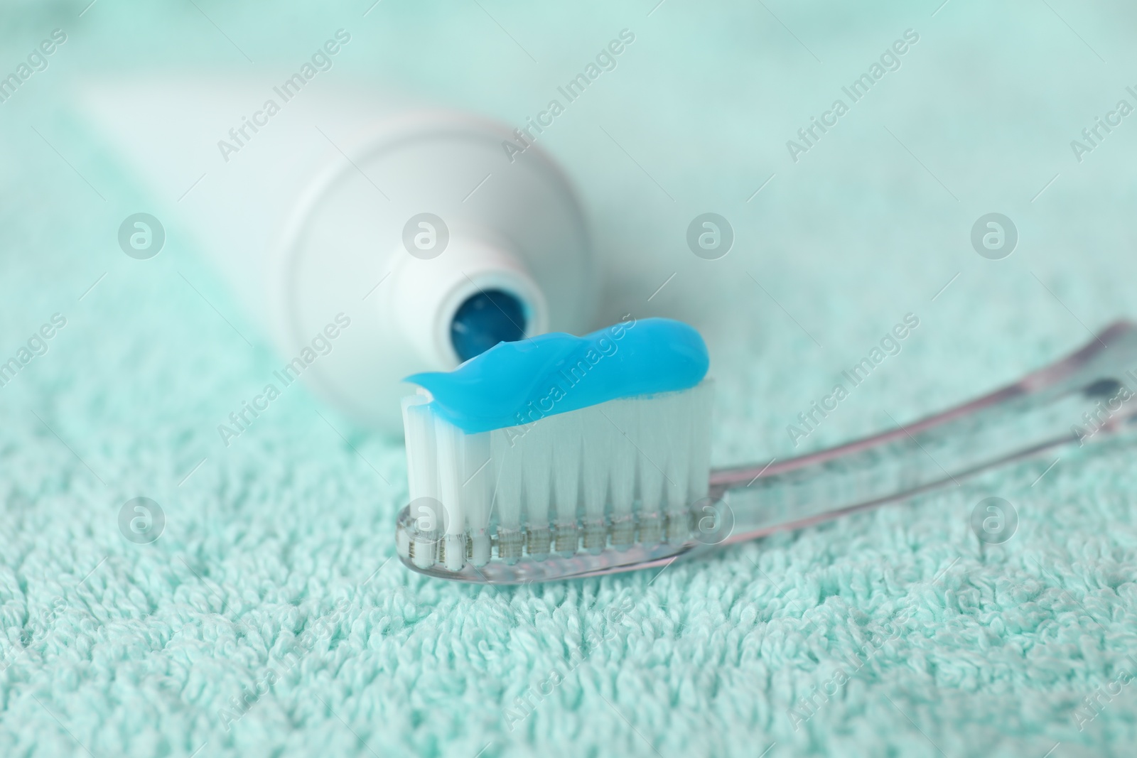 Toothbrush with toothpaste and tube on turquoise towel, closeup Photo of Toothbrush with toothpaste and tube on turquoise towel, closeup