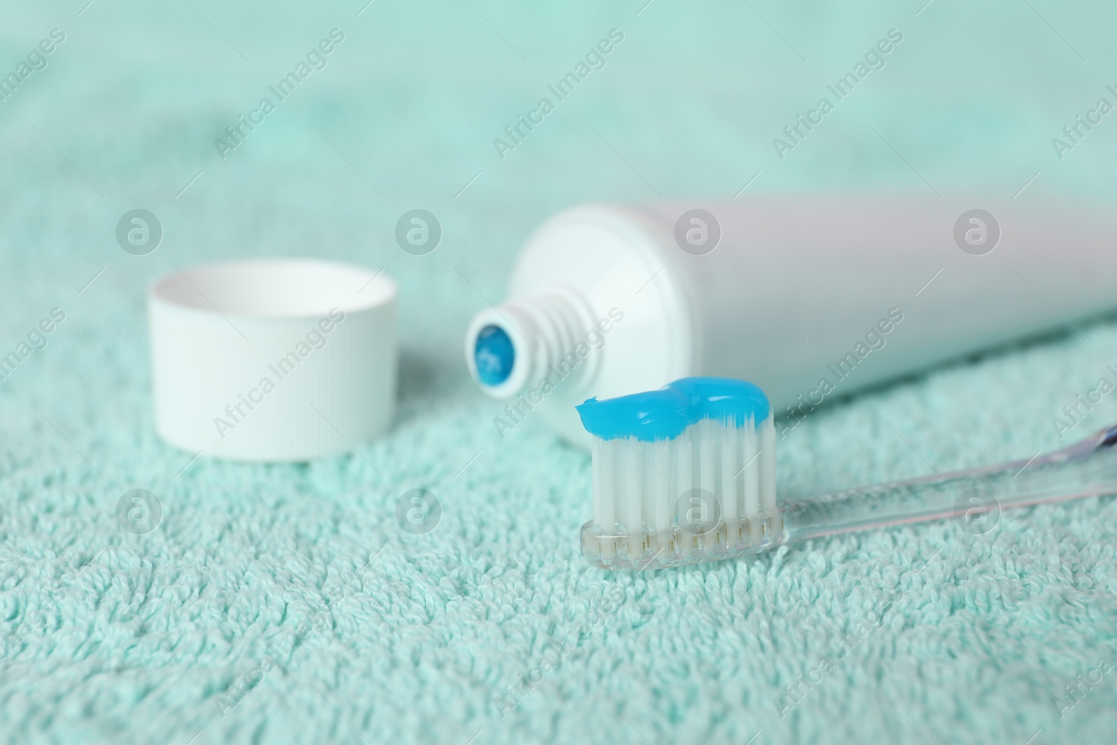 Toothbrush with toothpaste and tube on turquoise towel, closeup Photo of Toothbrush with toothpaste and tube on turquoise towel, closeup