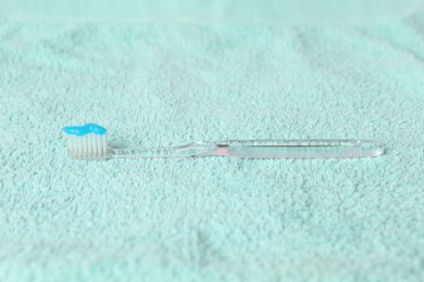 Photo of Toothbrush with toothpaste on turquoise towel, closeup