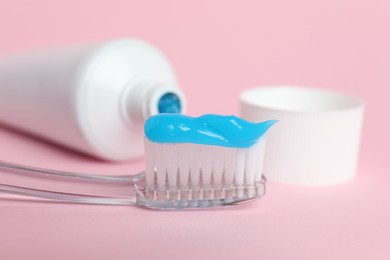 Photo of Toothbrush with toothpaste and tube on pink background, closeup