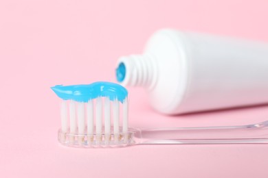 Photo of Toothbrush with toothpaste and tube on pink background, closeup