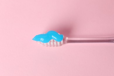 Photo of Toothbrush with toothpaste on pink background, top view