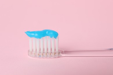 Photo of Toothbrush with toothpaste on pink background, closeup