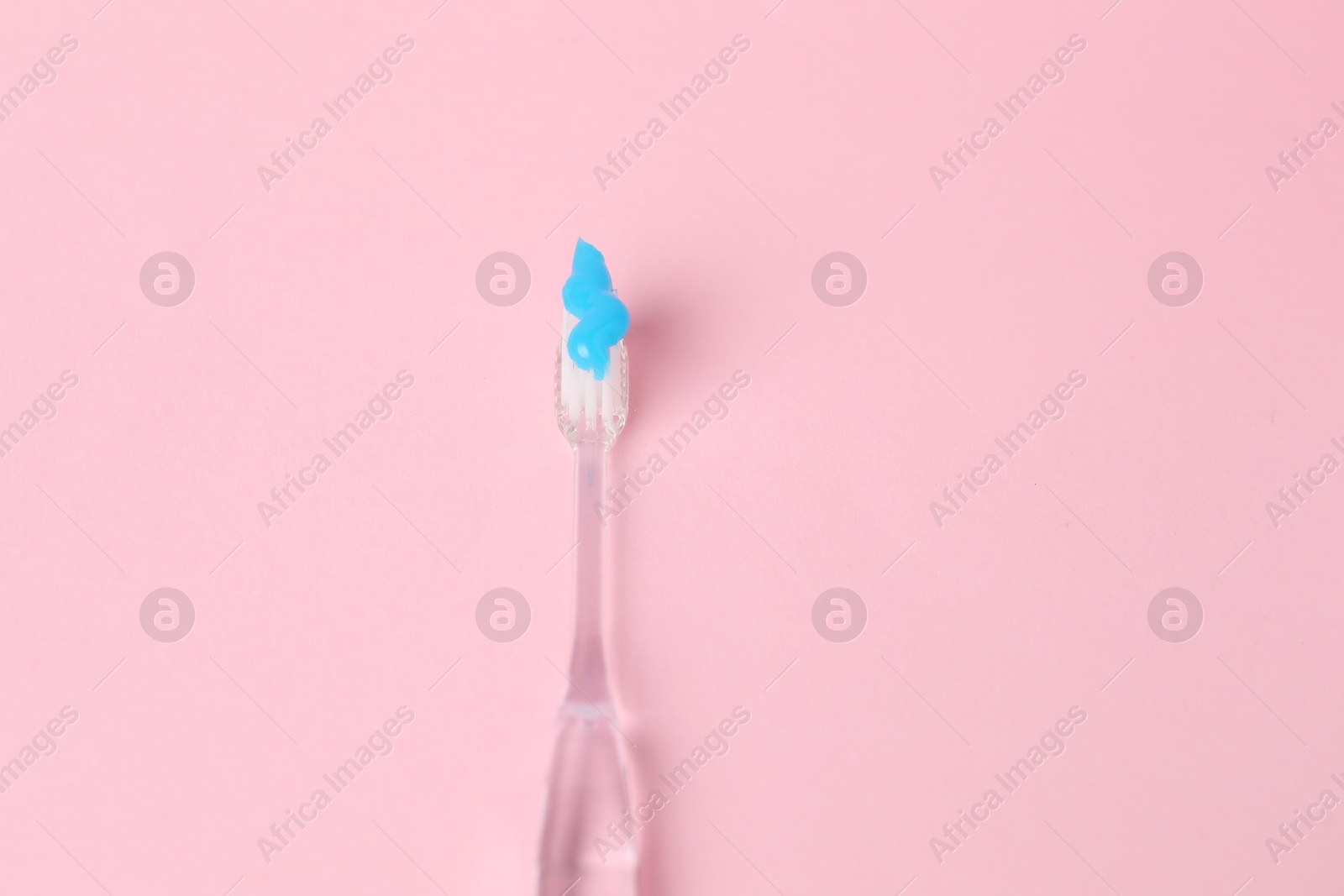 Photo of One toothbrush with toothpaste on pink background