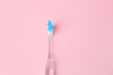 Photo of One toothbrush with toothpaste on pink background