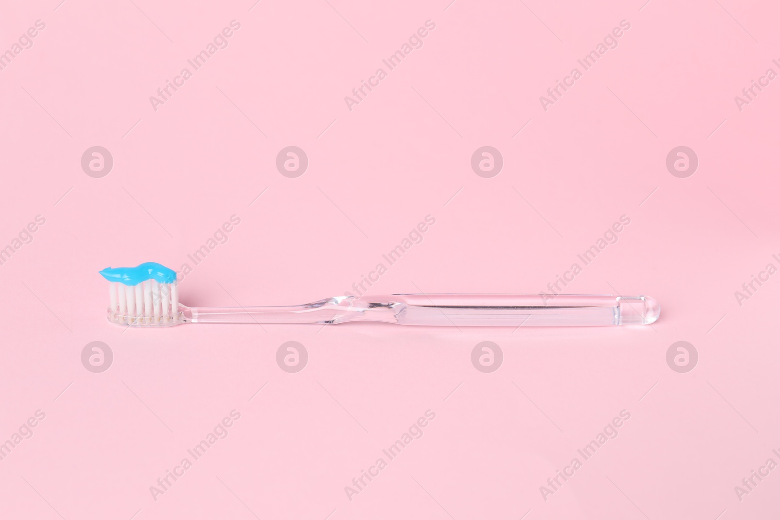 Photo of One toothbrush with toothpaste on pink background