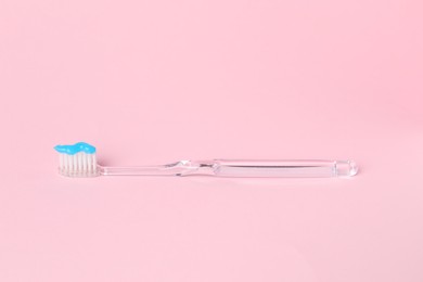 Photo of One toothbrush with toothpaste on pink background