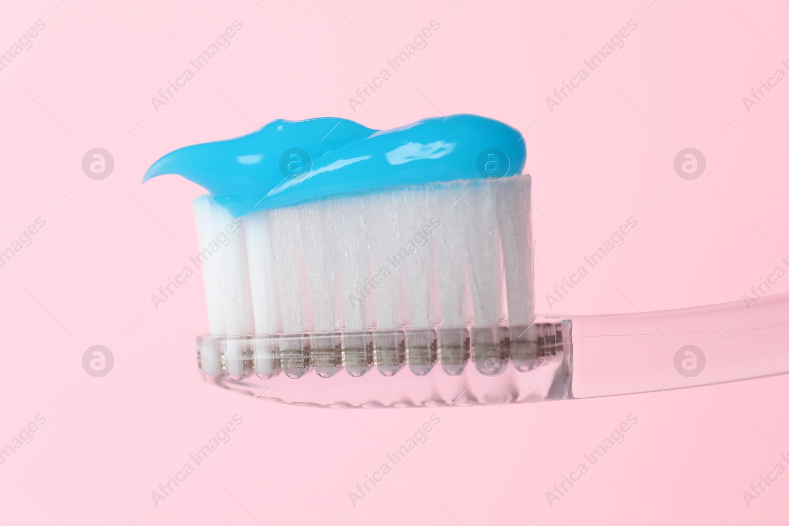 Photo of Toothbrush with toothpaste in air on pink background, closeup