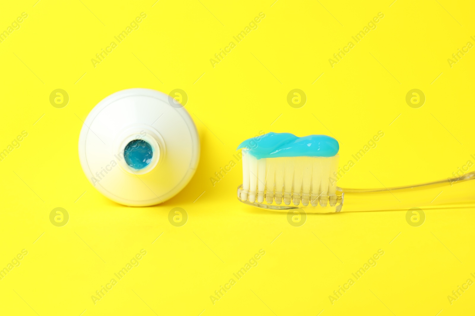 Photo of Toothbrush with toothpaste and tube on yellow background, closeup