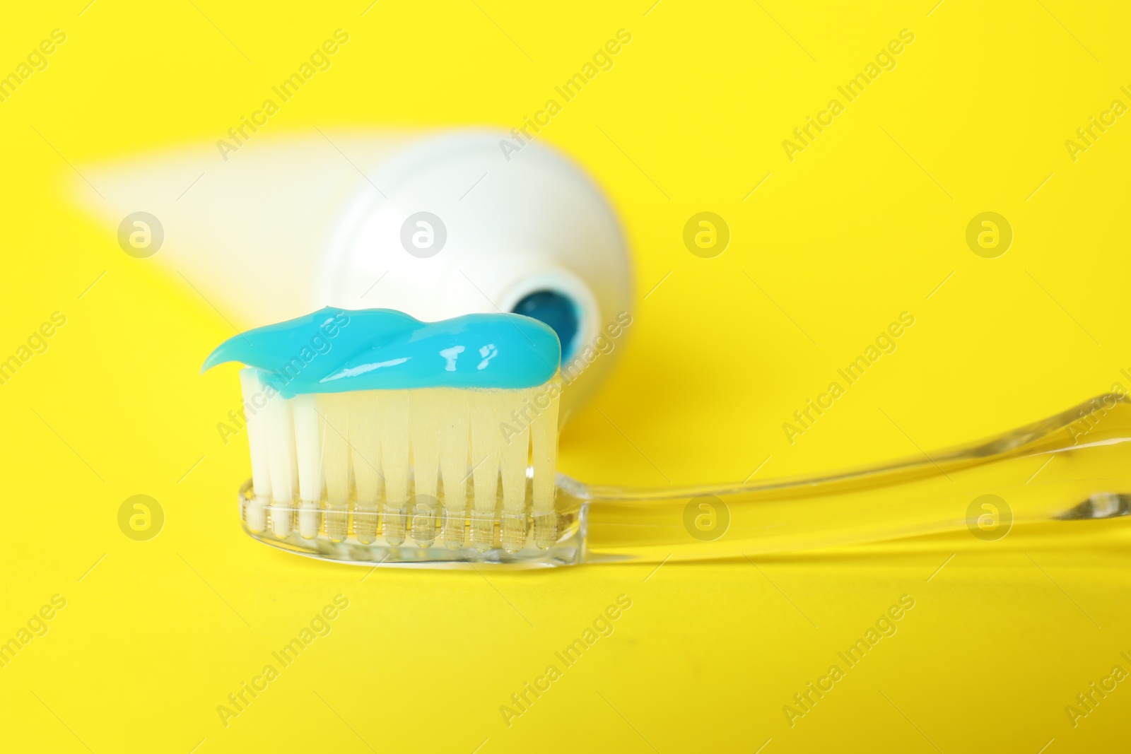 Photo of Toothbrush with toothpaste and tube on yellow background, closeup