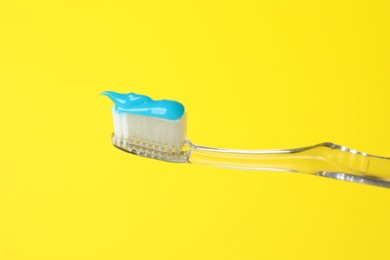 Photo of Toothbrush with toothpaste in air on yellow background, closeup