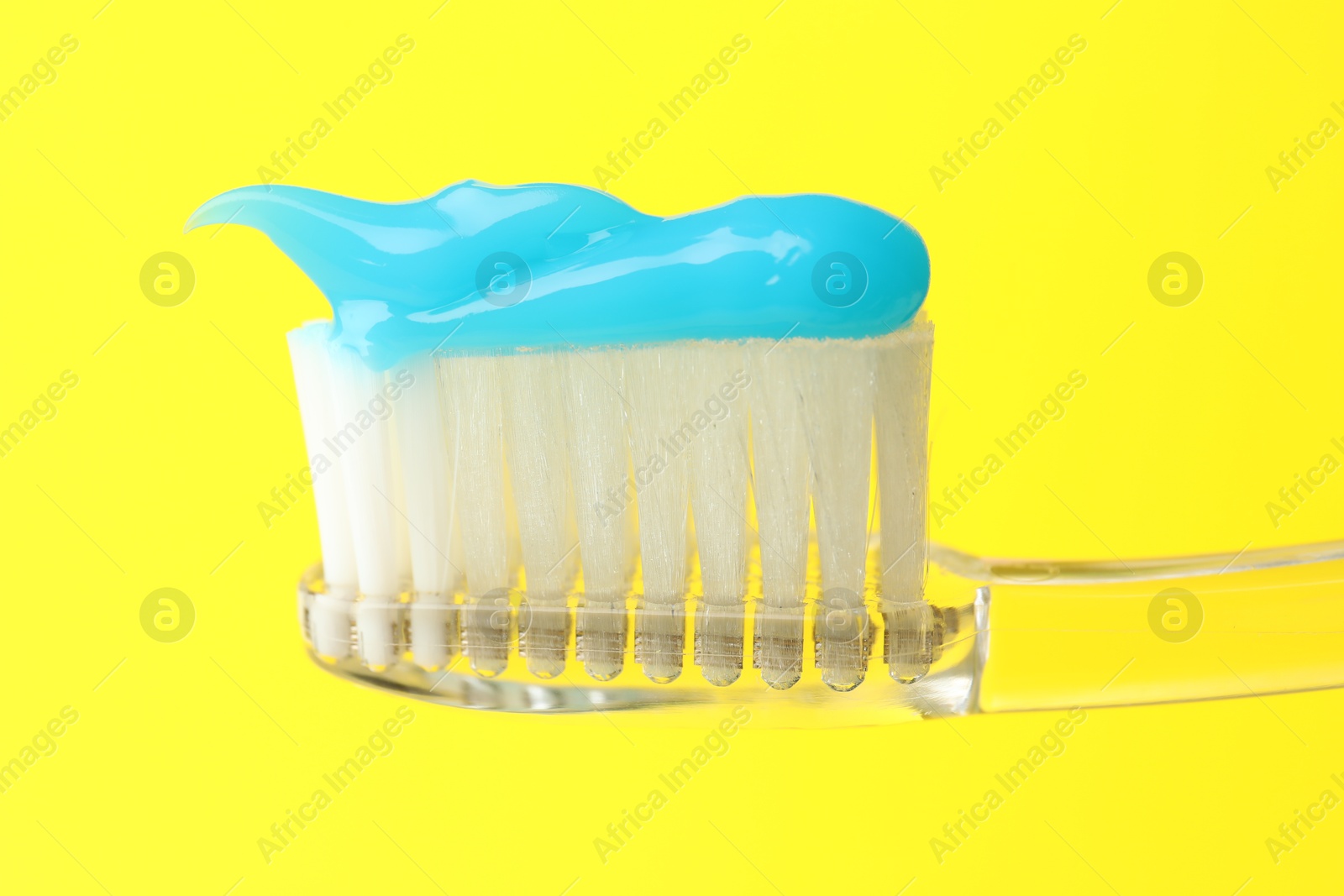 Photo of Toothbrush with toothpaste in air on yellow background, closeup