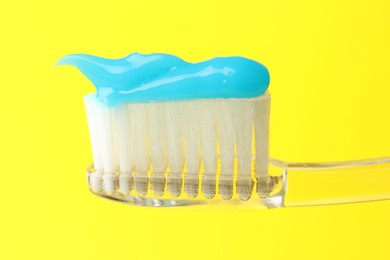 Photo of Toothbrush with toothpaste in air on yellow background, closeup