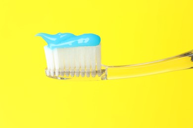 Photo of Toothbrush with toothpaste in air on yellow background, closeup