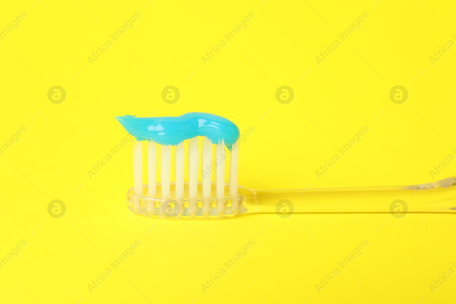 Toothbrush with toothpaste in air on yellow background, closeup Photo of Toothbrush with toothpaste in air on yellow background, closeup