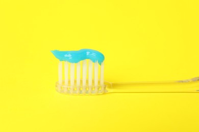 Photo of Toothbrush with toothpaste in air on yellow background, closeup