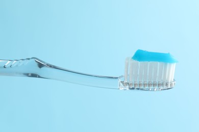 Photo of Toothbrush with toothpaste in air on light blue background, closeup