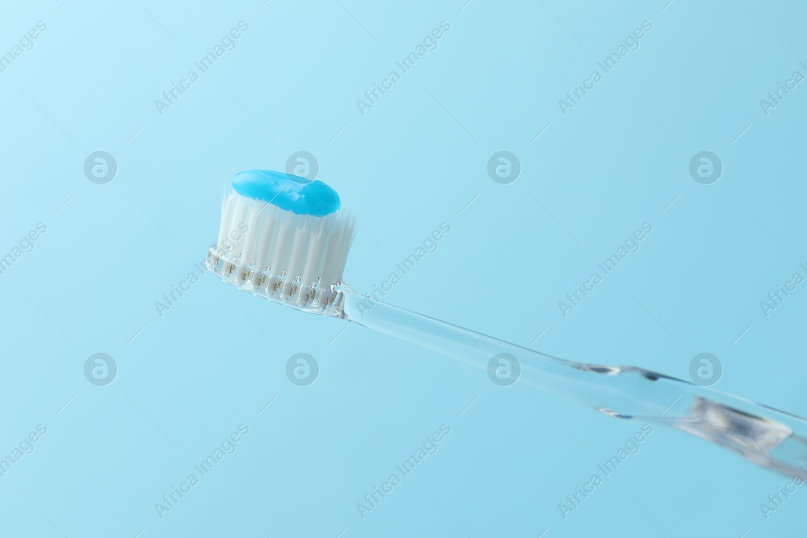 Toothbrush with toothpaste in air on light blue background, closeup Photo of Toothbrush with toothpaste in air on light blue background, closeup