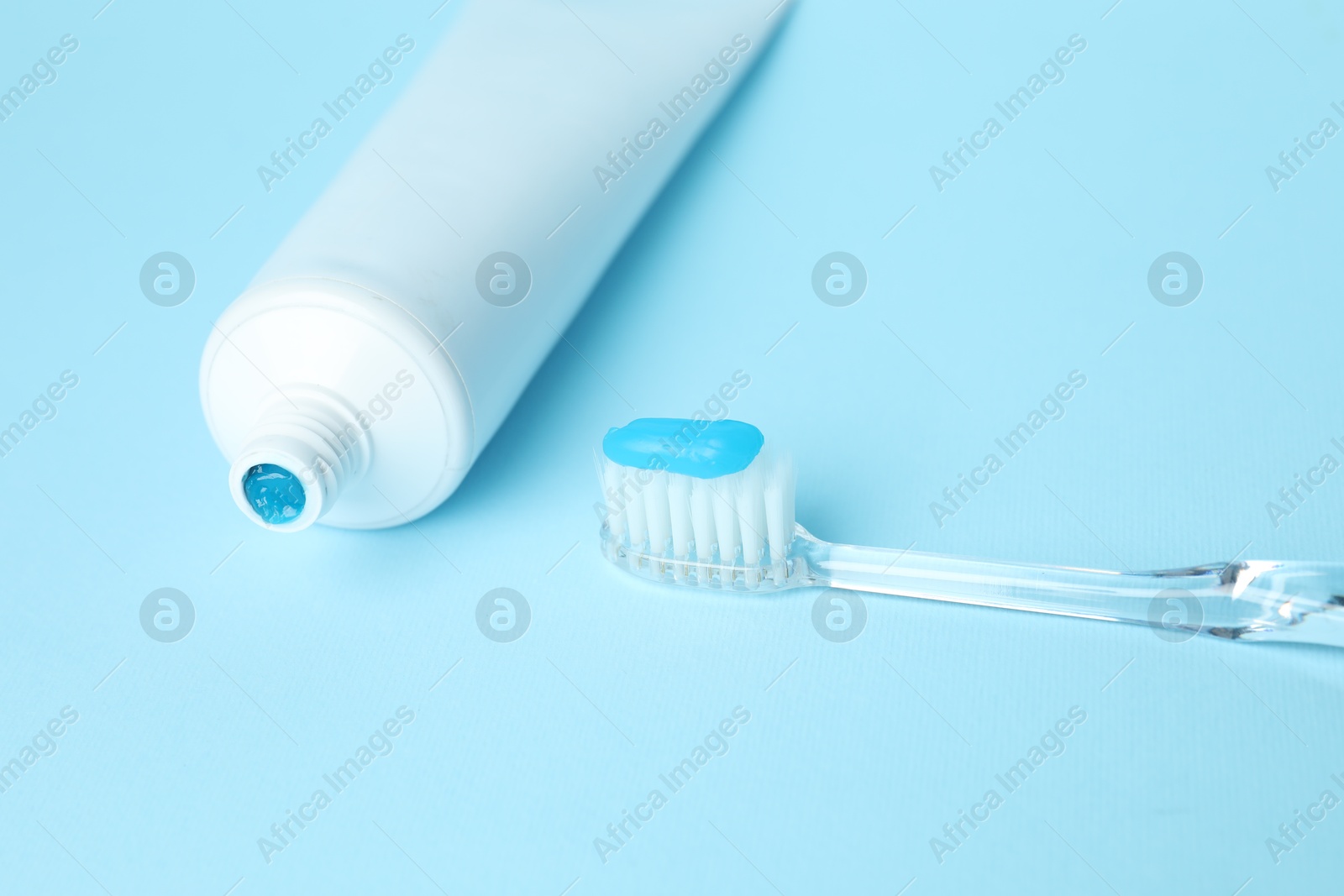 Photo of Toothbrush with toothpaste and tube on light blue background