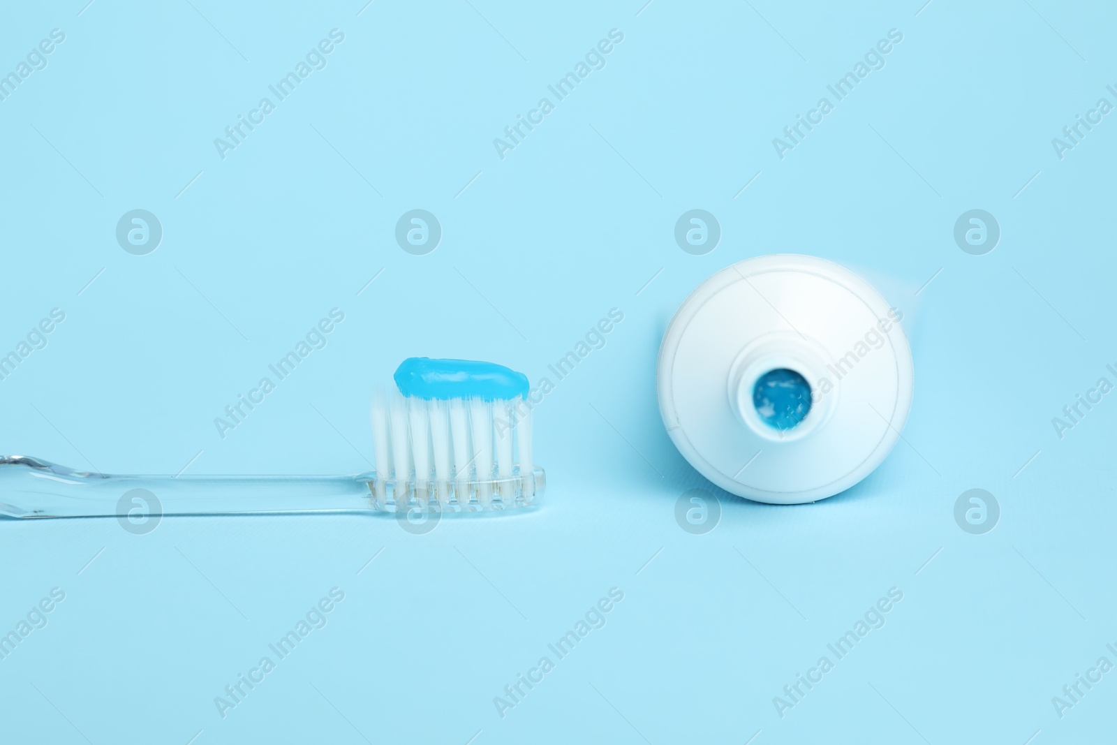 Toothbrush with toothpaste and tube on light blue background Photo of Toothbrush with toothpaste and tube on light blue background