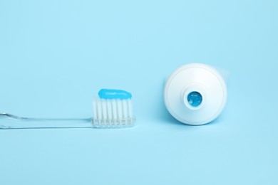 Photo of Toothbrush with toothpaste and tube on light blue background