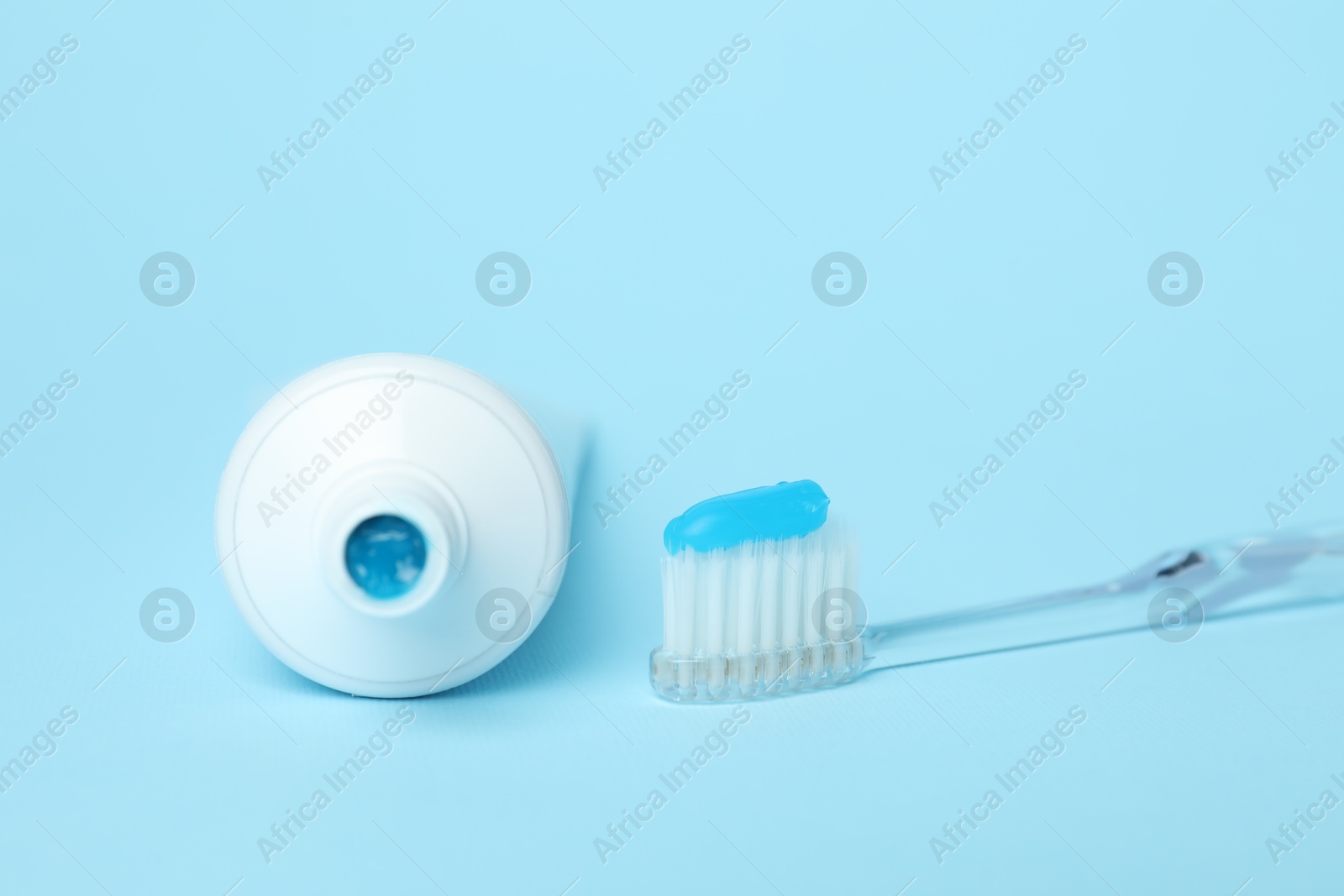 Photo of Toothbrush with toothpaste and tube on light blue background