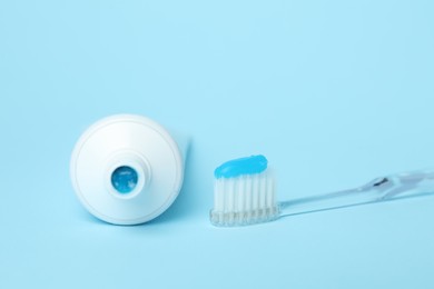 Photo of Toothbrush with toothpaste and tube on light blue background