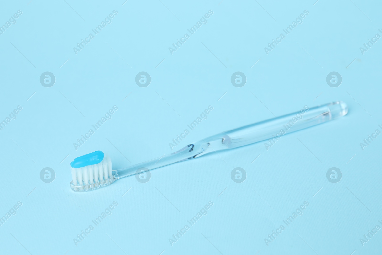 Toothbrush with toothpaste on light blue background Photo of Toothbrush with toothpaste on light blue background