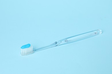 Photo of Toothbrush with toothpaste on light blue background