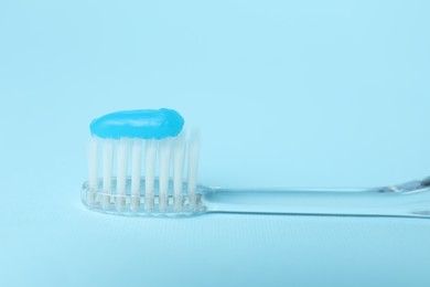 Photo of Toothbrush with toothpaste on light blue background, closeup