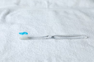 Photo of One toothbrush with toothpaste on white towel