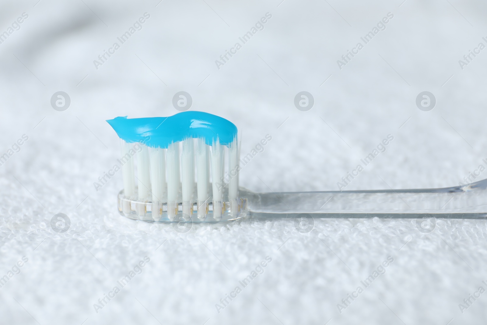 Photo of Toothbrush with toothpaste on white towel, closeup