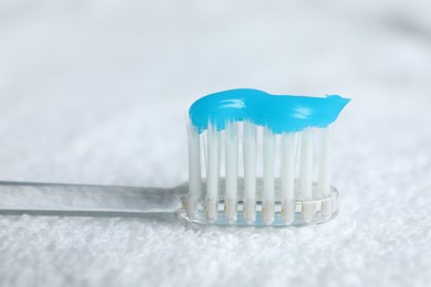 Photo of Toothbrush with toothpaste on white towel, closeup