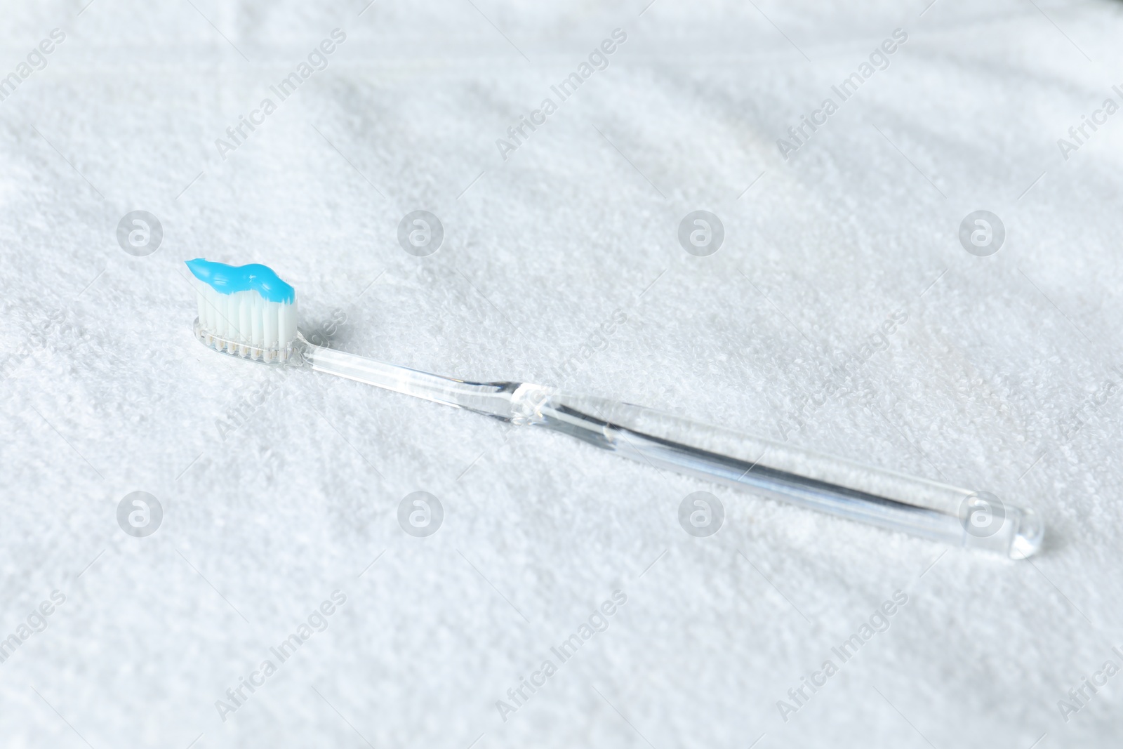 One toothbrush with toothpaste on white towel Photo of One toothbrush with toothpaste on white towel